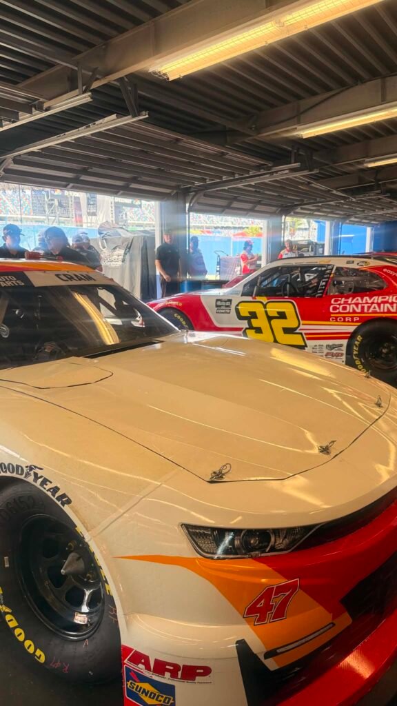 Stock cars with sponsor graphics parked together in a garage